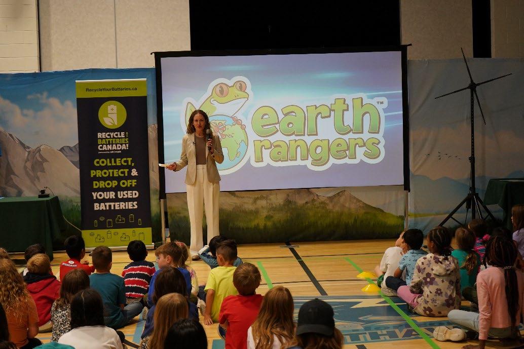 Earth Rangers President Tovah Barocas speaks to students at a school assembly, with a Recycle Your Batteries, Canada! banner on stage.