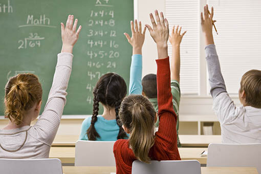 Kids raising their hands in a classroom