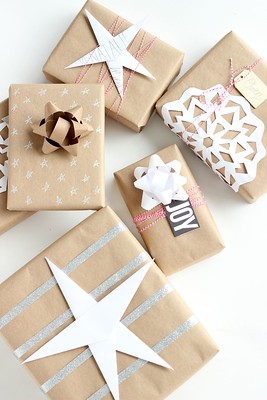 a pile of six gifts wrapped with eco-friendly kraft paper, with a mix of paper decorations and coloured string.